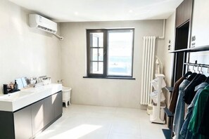 Un baño moderno con un ventanal grande, un inodoro y un tocador con lavamanos.