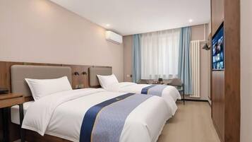 A hotel room with two beds, a desk, a TV, and a wardrobe.