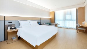 A modern hotel room with a large bed, bedside tables, a desk, and a window with sheer curtains. - Ji Hotel (government Shop, Ouhai District, Wenzhou (Wenzhou)