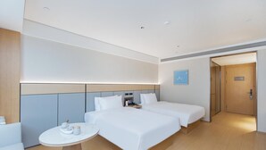 A modern hotel room with two beds, a small round table with tea set, and a door leading to a hallway. - Ji Hotel (government Shop, Ouhai District, Wenzhou (Wenzhou)