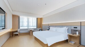 A modern hotel room with a large bed, a desk, and a seating area. - Ji Hotel (government Shop, Ouhai District, Wenzhou (Wenzhou)