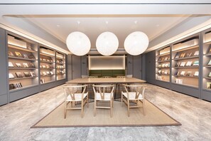 A modern library with a central table and chairs, surrounded by bookshelves. - Ji Hotel (Kaifeng)