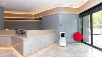 A modern reception area with a marble counter, a fire extinguisher, and a red chair.