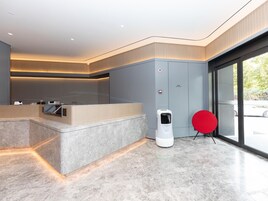 A modern reception area with a marble counter, a fire extinguisher, and a red chair.