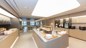 A modern hotel kitchen with a central island, dining area, and kitchen appliances. - Ji Hotel (Kaifeng)