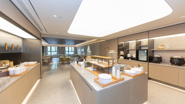 A modern hotel kitchen with a central island, dining area, and kitchen appliances. - Ji Hotel (Kaifeng)