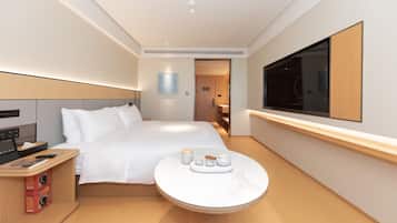 A modern hotel room with a bed, bedside table, and a round table with tea set.