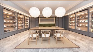 A modern library with a central table and chairs, surrounded by bookshelves. - Ji Hotel (Kaifeng)
