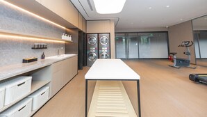 A modern hotel room with a large bed, a desk, a washing machine, and a treadmill. - Ji Hotel (Kaifeng)