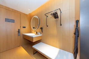 A modern bathroom with a wooden vanity, a mirror with a light, a towel rack, and a bench. - Ji Hotel (Kaifeng)