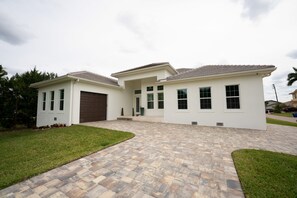 A modern two-story house with a paved driveway, a garage, and a well-maintained lawn.