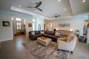A spacious living room with a sectional sofa, ottoman, and patterned armchair.