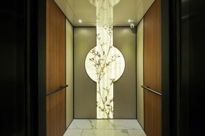 An elevator with a modern design, featuring a central decorative panel with a floral pattern.
