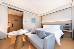 Una habitación de hotel moderna con una cama, un sofá, una mesita y una mesita de noche.