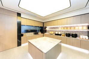 A modern kitchen with a central island, built-in appliances, and a marble countertop. - Ji Hotel (Xi'an)