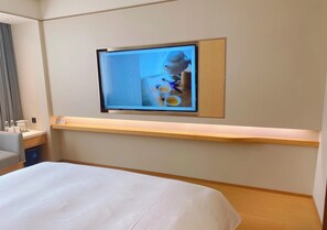 A hotel room with a bed, a desk with a computer, and a TV mounted on the wall. - Ji Hotel (Xi'an)
