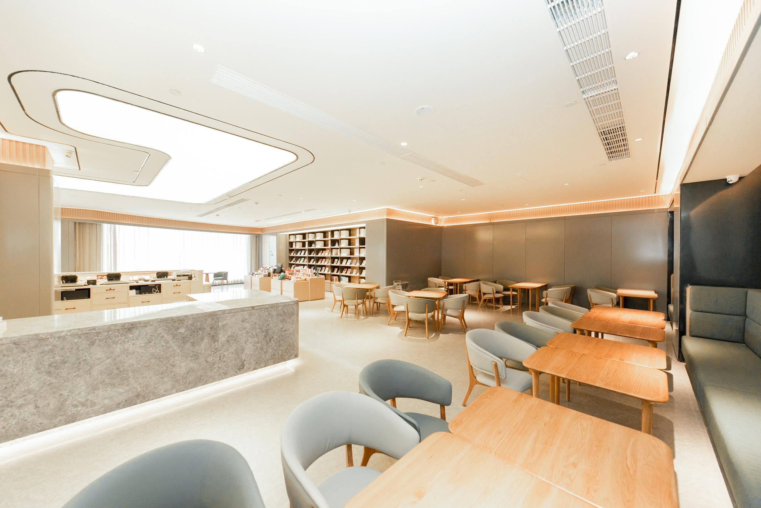 Een modern interieur met een centraal gelegen balie, zithoek en boekenkasten.