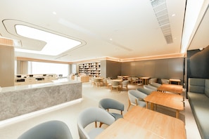 A modern interior with a central counter, seating area, and bookshelves.