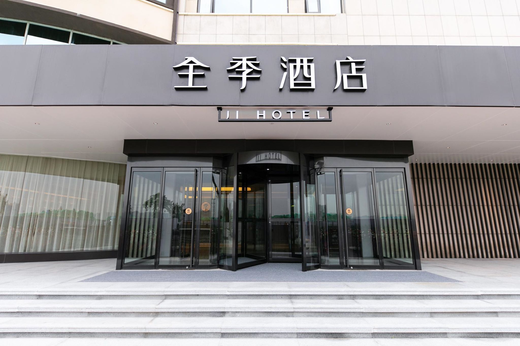 The entrance to a hotel with a modern design, featuring a glass door entrance and a sign above.