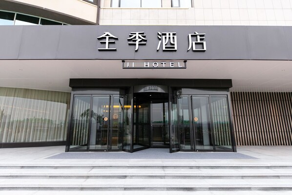 The entrance to a hotel with a modern design, featuring a glass door entrance and a sign above. - Ji Hotel (Xi'an)