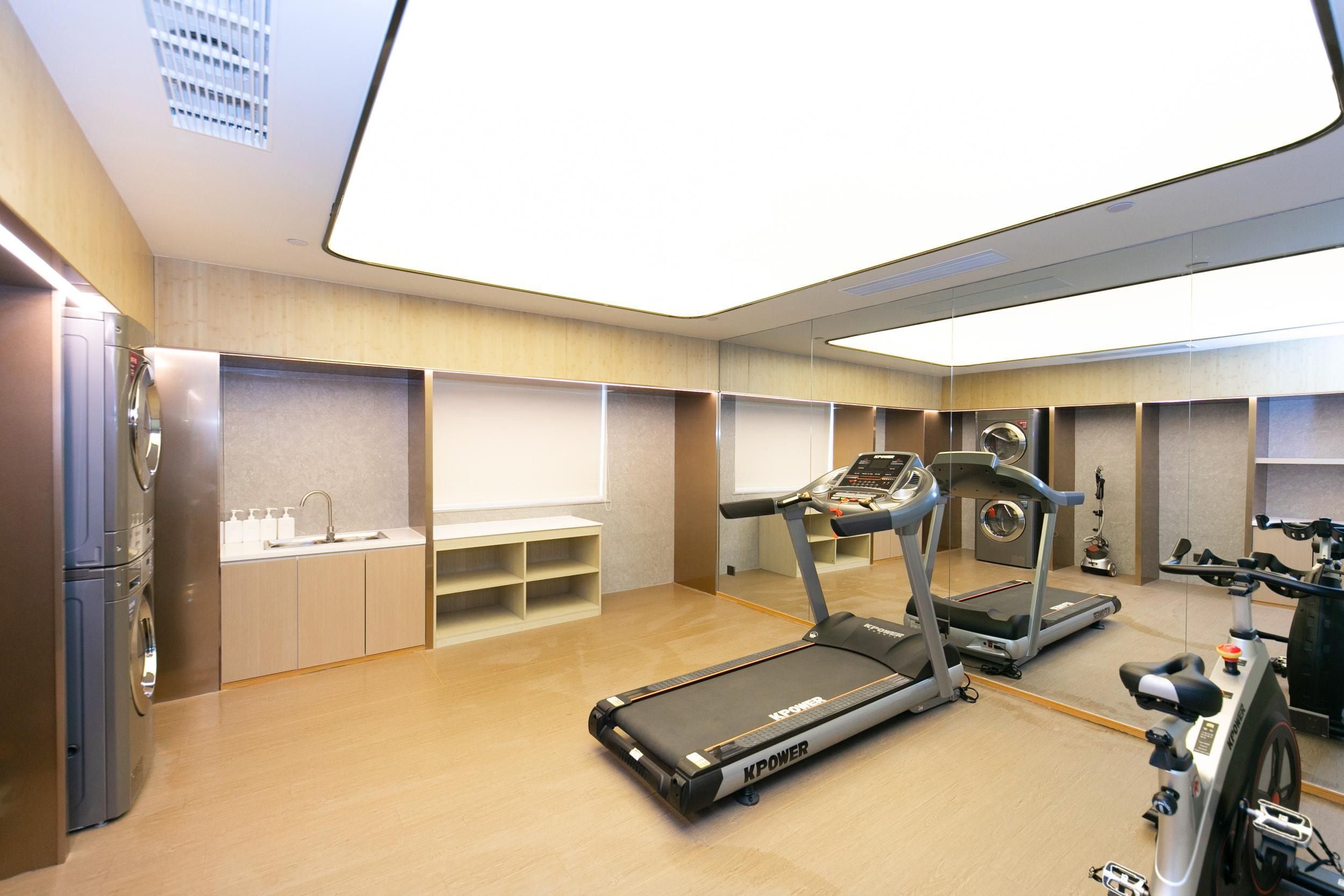 A modern gym with treadmills, a stationary bike, and a washing machine.