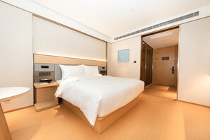 A modern hotel room with a large bed, bedside table, and a small round table. - Ji Hotel (Xi'an)
