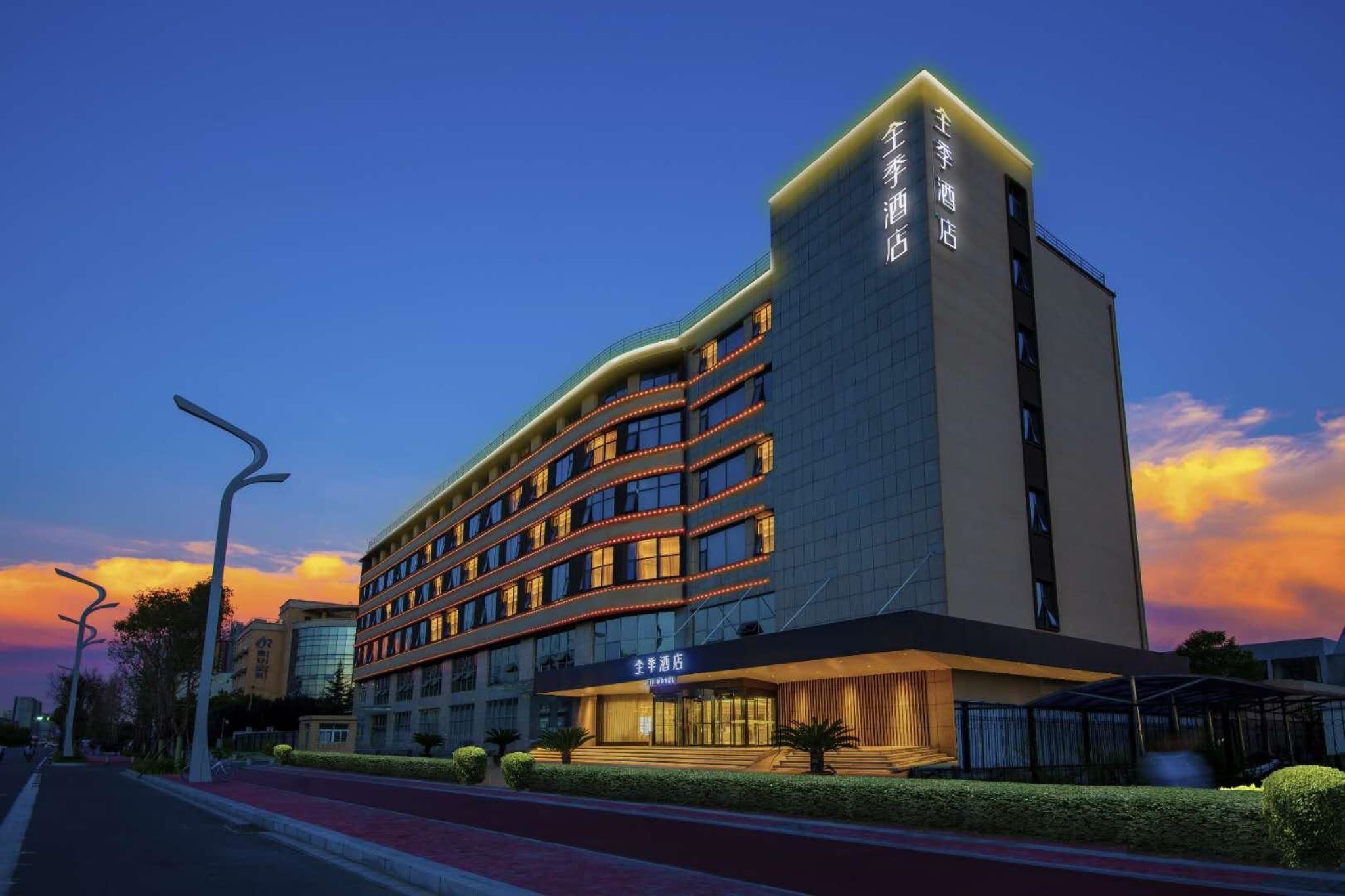 A multi-story hotel with a modern design, featuring a prominent entrance and a well-lit facade.