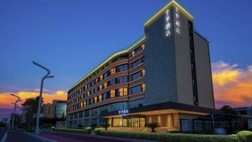 A multi-story hotel with a modern design, featuring a prominent entrance and a well-lit facade.