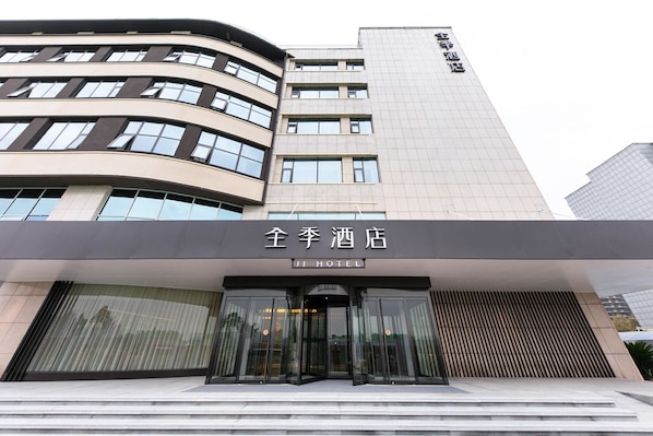 A hotel entrance with a modern design, featuring a curved facade and a prominent entrance with glass doors.