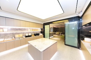 A modern kitchen with marble countertops, wooden cabinets, and a central island.