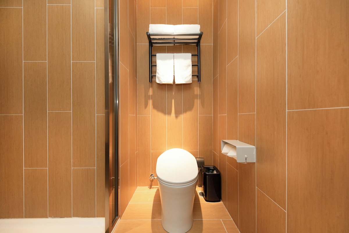 A modern bathroom with a toilet, a towel rack, and a trash bin.
