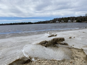A frozen lake with ice formations and houses in the background.