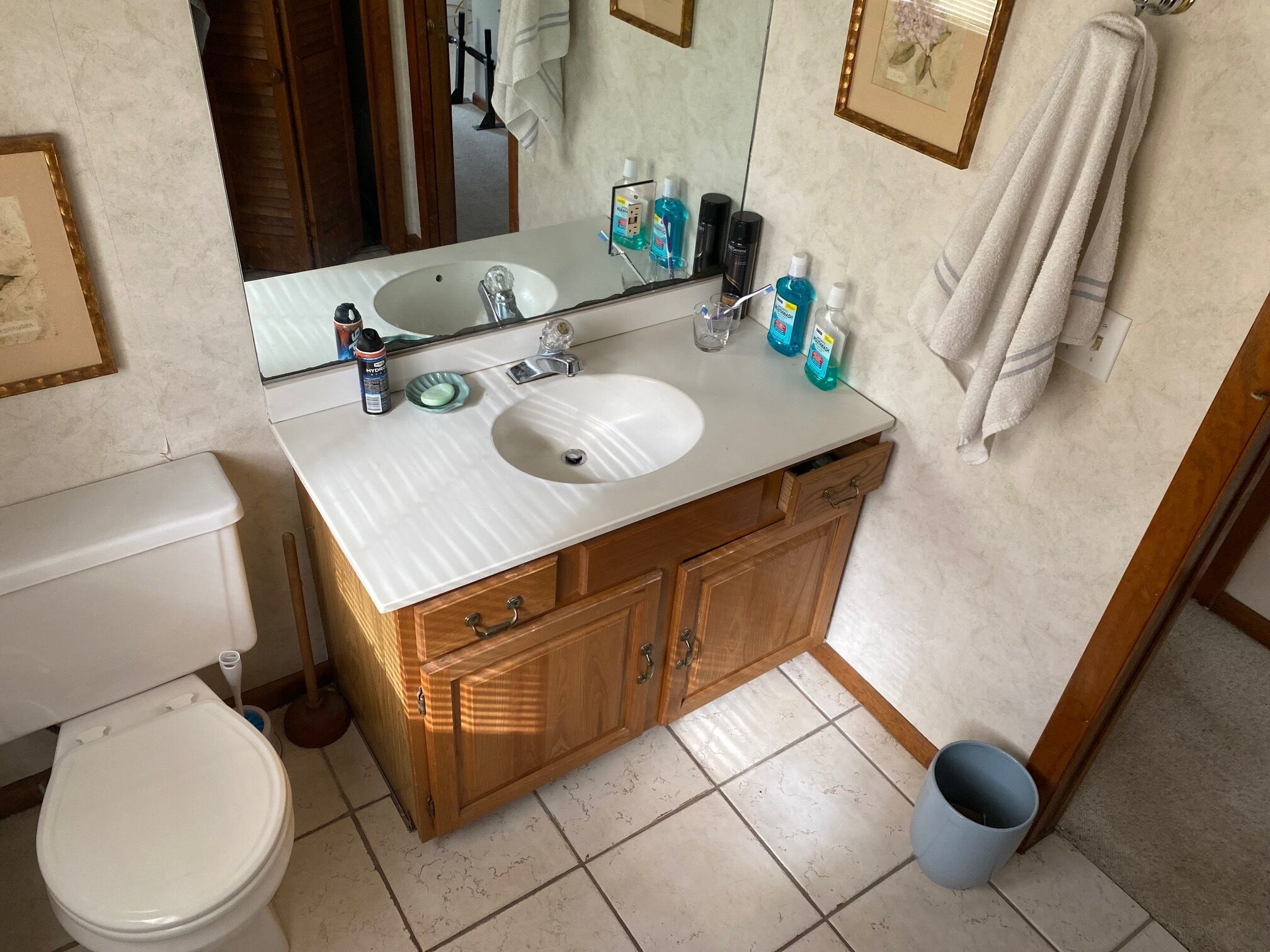 Een badkamer met een wit wastafel, houten kastjes, een spiegel en een toilet.