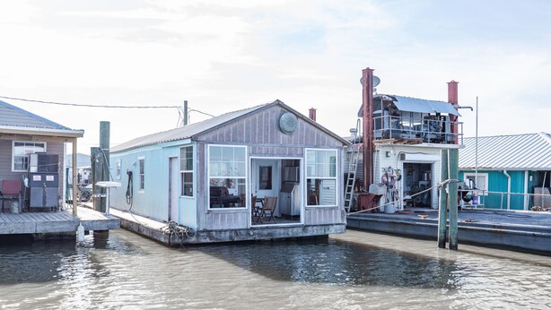 Une maison flottante dotée d’un quai, d’une petite terrasse et d’une grande fenêtre.