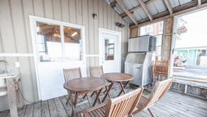 Une terrasse en bois avec une table et des chaises en bois, un réfrigérateur et un évier.