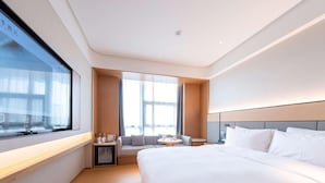 A hotel room with a large bed, a seating area with a table, and a window with curtains. - Ji Hotel Nantong Motor East Station (Nantong)
