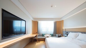 A modern hotel room with a large bed, a desk, a chair, a small table, and a TV mounted on the wall. - Ji Hotel (future Road Store, Convention & Exhibiti (Zhengzhou)