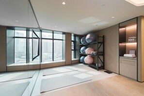 Una habitación moderna con ventanas amplias, una colchoneta de yoga y un estante con pelotas de ejercicio.