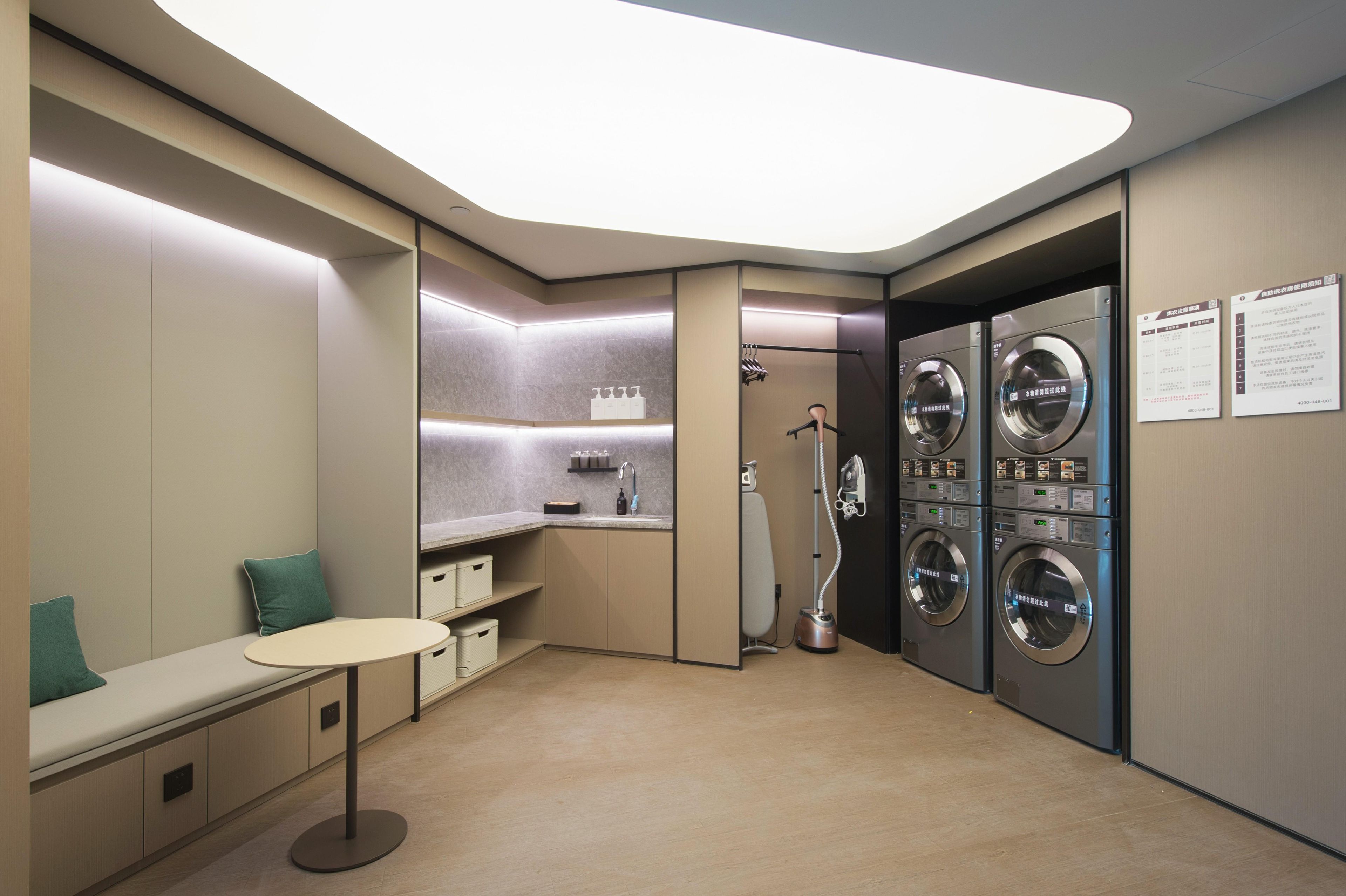 Ein modernes Badezimmer mit Sitzgelegenheit, einem Waschbecken und zwei an der Wand befestigten Waschmaschinen.