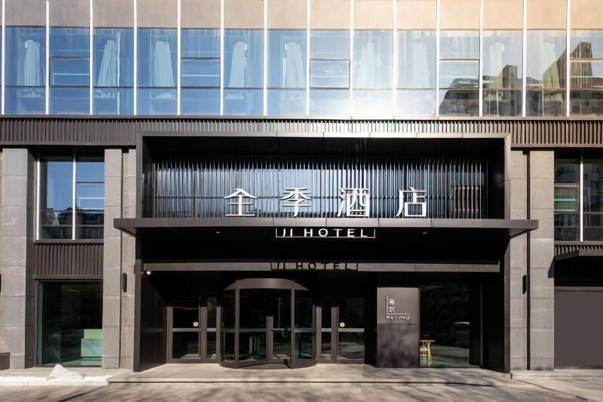 A hotel entrance with a modern facade, large windows, and a clear sign indicating the hotel name.