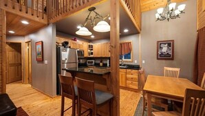 A wooden interior with a kitchen, dining area, and a staircase.