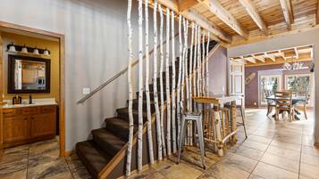 A staircase with a unique wooden railing design, a kitchen area with wooden cabinets, and a dining area with a table and chairs.
