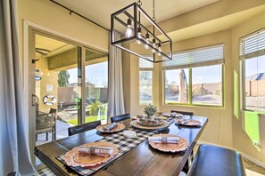 Enjoy meals in this beautifully set dining area with a long table, placemats, and a potted plant centerpiece.