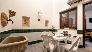 A dining area with a table set for four, a wall-mounted light fixture, and a window with a view of the outside. - I Tre Golfi Corallo Apartment (San Vito Lo Capo)