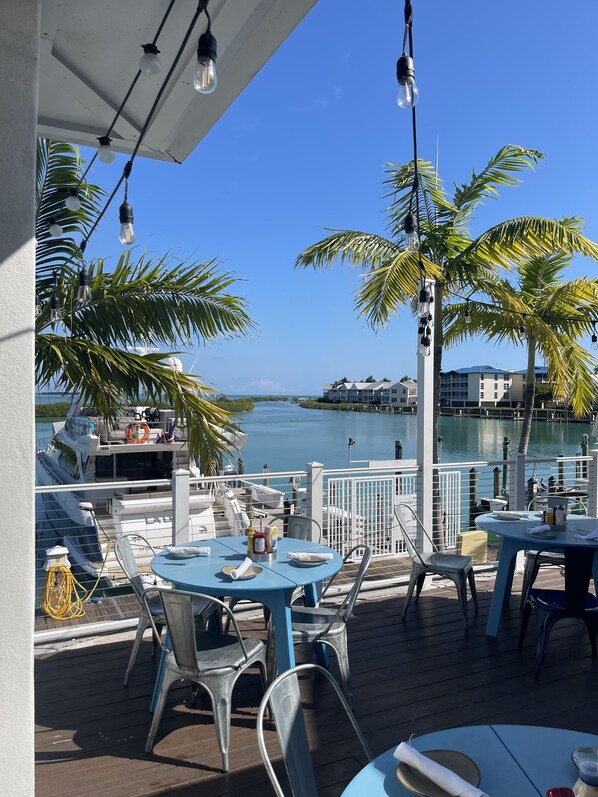 A deck with outdoor seating, overlooking a marina and a body of water.
