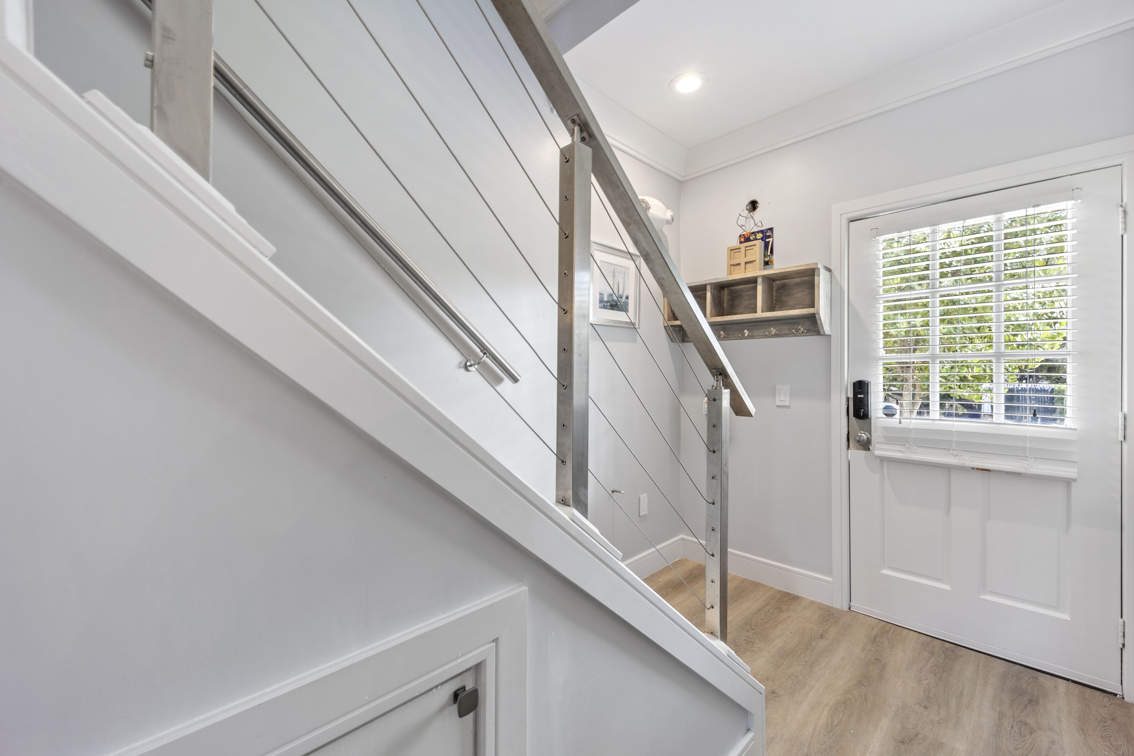 Una escalera con barandilla de metal y una puerta blanca con ventana.