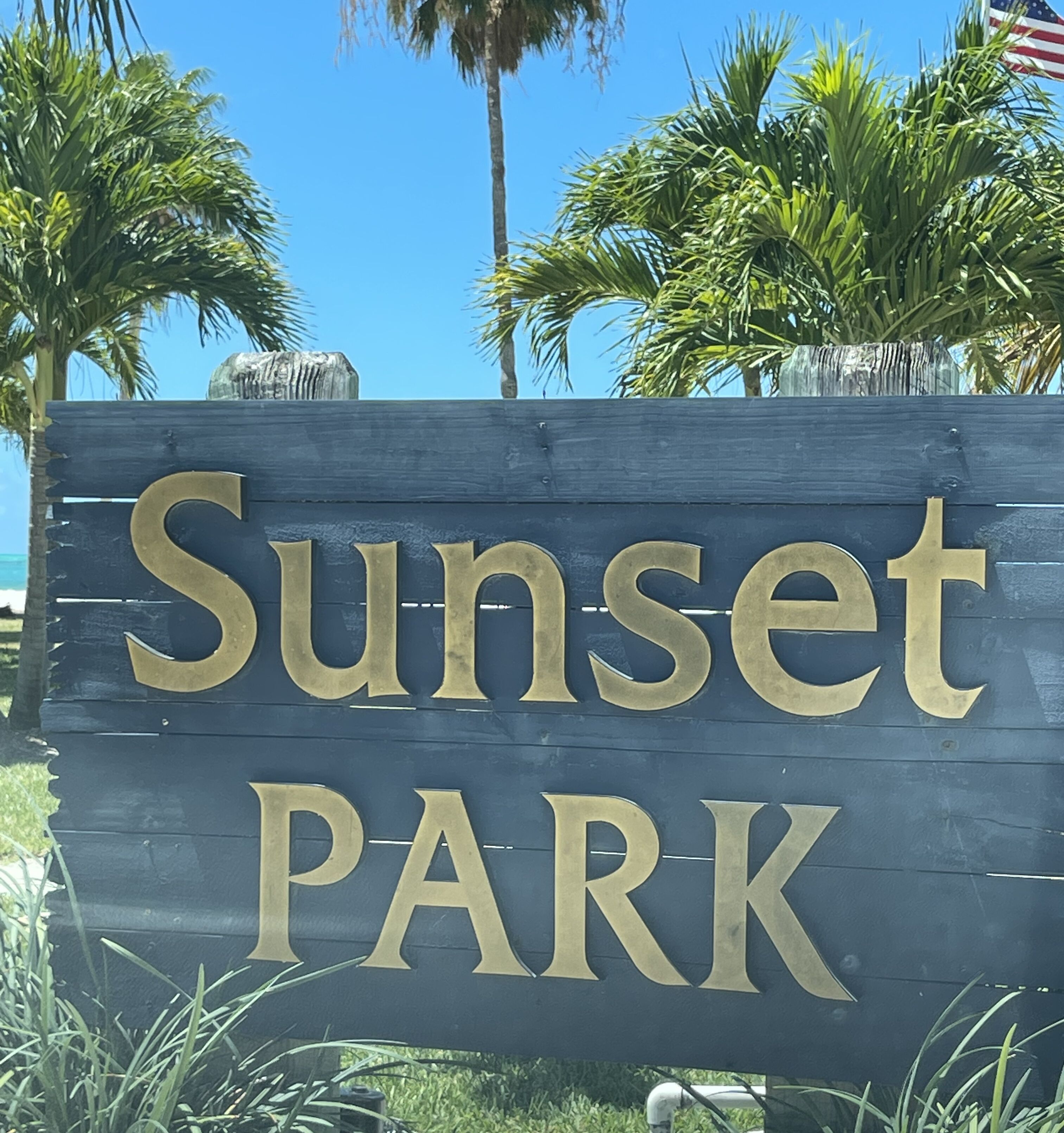 A wooden sign with the words "Sunset PARK" in large, gold letters.
