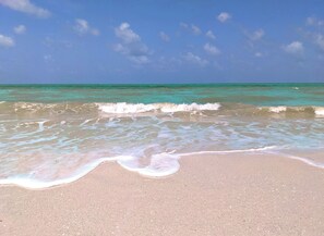 Une plage à l’eau turquoise et limpide, où les vagues sont douces.