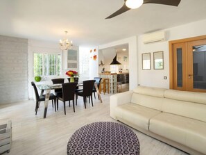 Een moderne woonkamer met een bank, een eettafel met stoelen en een gestreept voetenbankje.