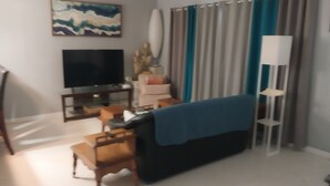 Un salon avec un téléviseur, un canapé, une table basse et un lampadaire.